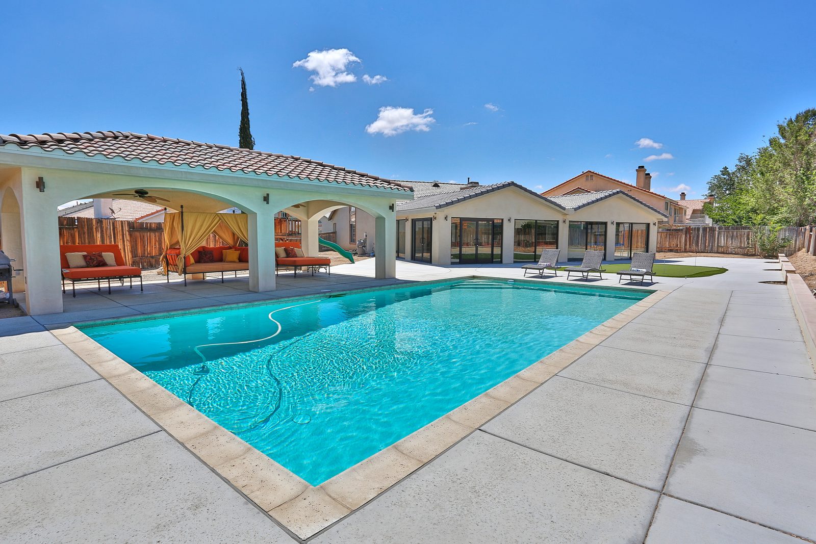A backyard pool beside a covered patio