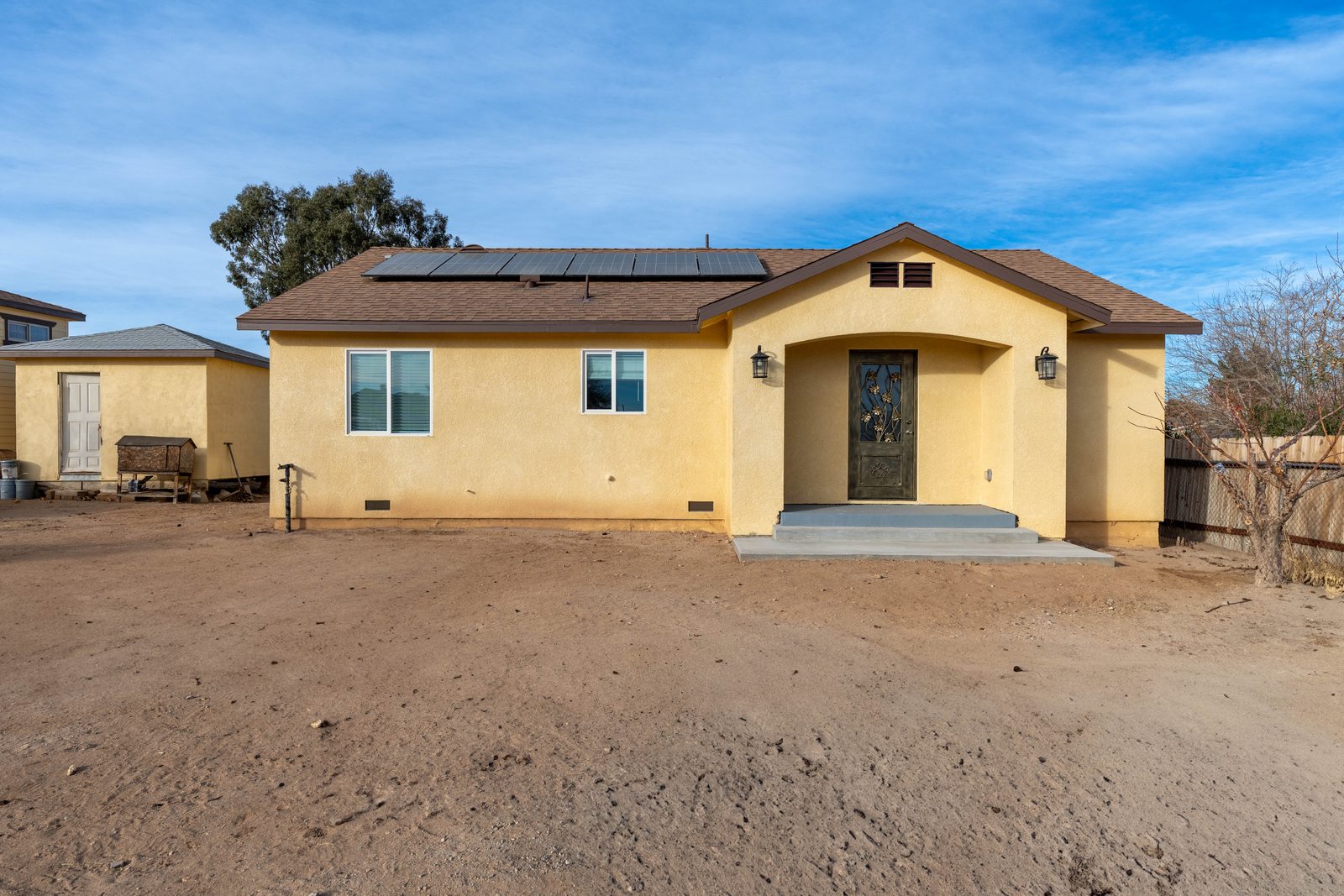 A yellow stucco house with solar panels on the roof